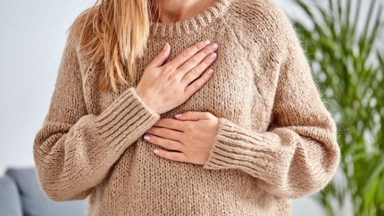 Extrasystolen: Frau hält Hand auf Brust bei Herzstolpern