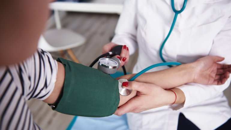 Ärztin misst mit Blutdruckmanschette den Blutdruck
