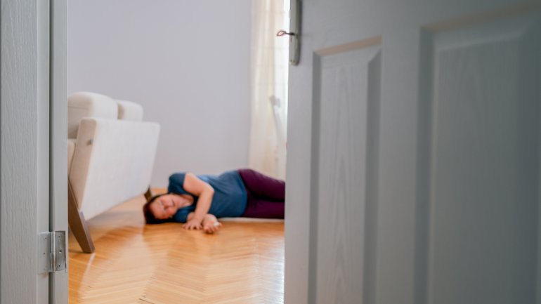 Frau mit Schlaganfall liegt bewusstlos auf dem Boden
