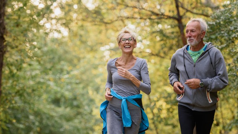 Älteres Paar geht im Wald joggen, um ihr Herz gesund zu halten