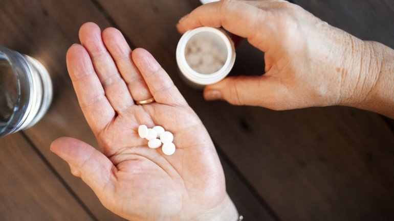 Ältere Frau nimmt Kalziumantagonisten als Tabletten
